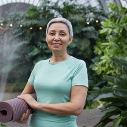 Older woman finishing yoga outside.