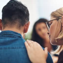 Partner holding her hand on her partner's shoulder at the doctor's office