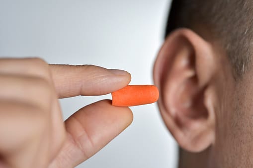 Young man putting an earplug into his ear