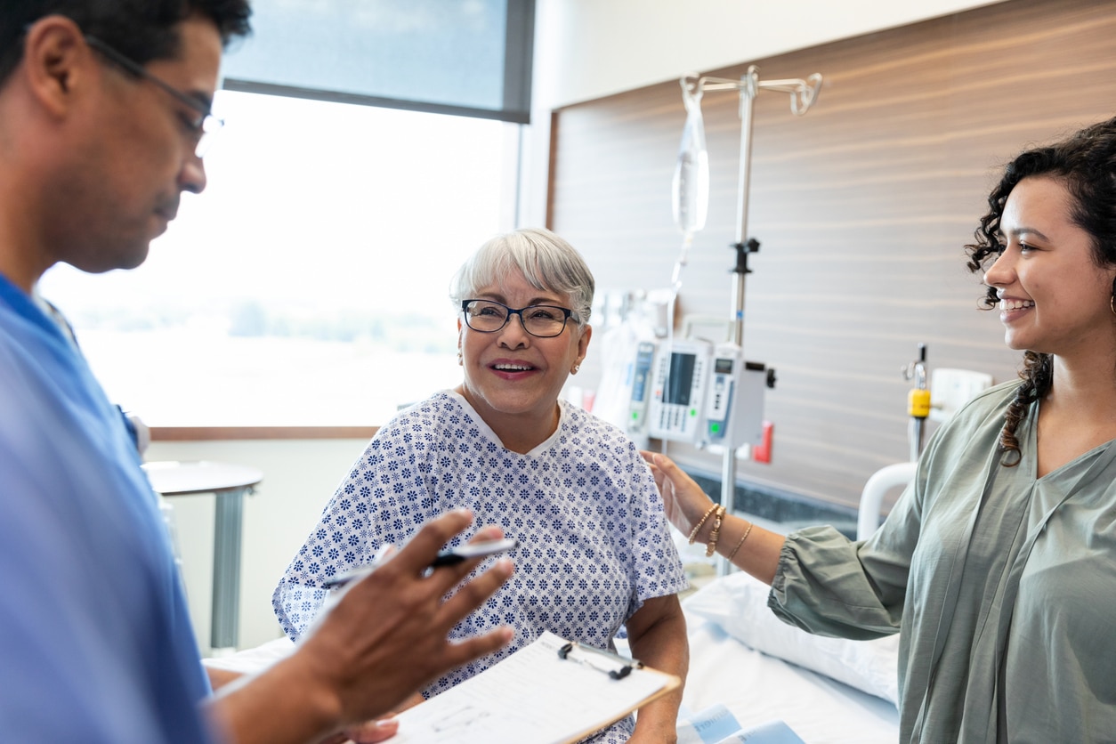 Happy Patient with Doctor and Family in Hospital Room.