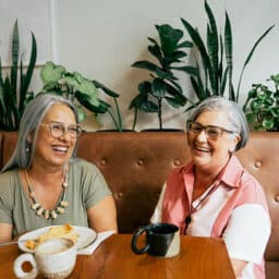 Two friends chatting in a cafe drinking coffee.