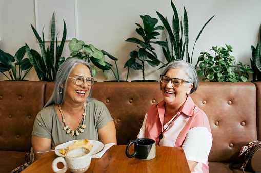 Two friends chatting in a cafe drinking coffee.